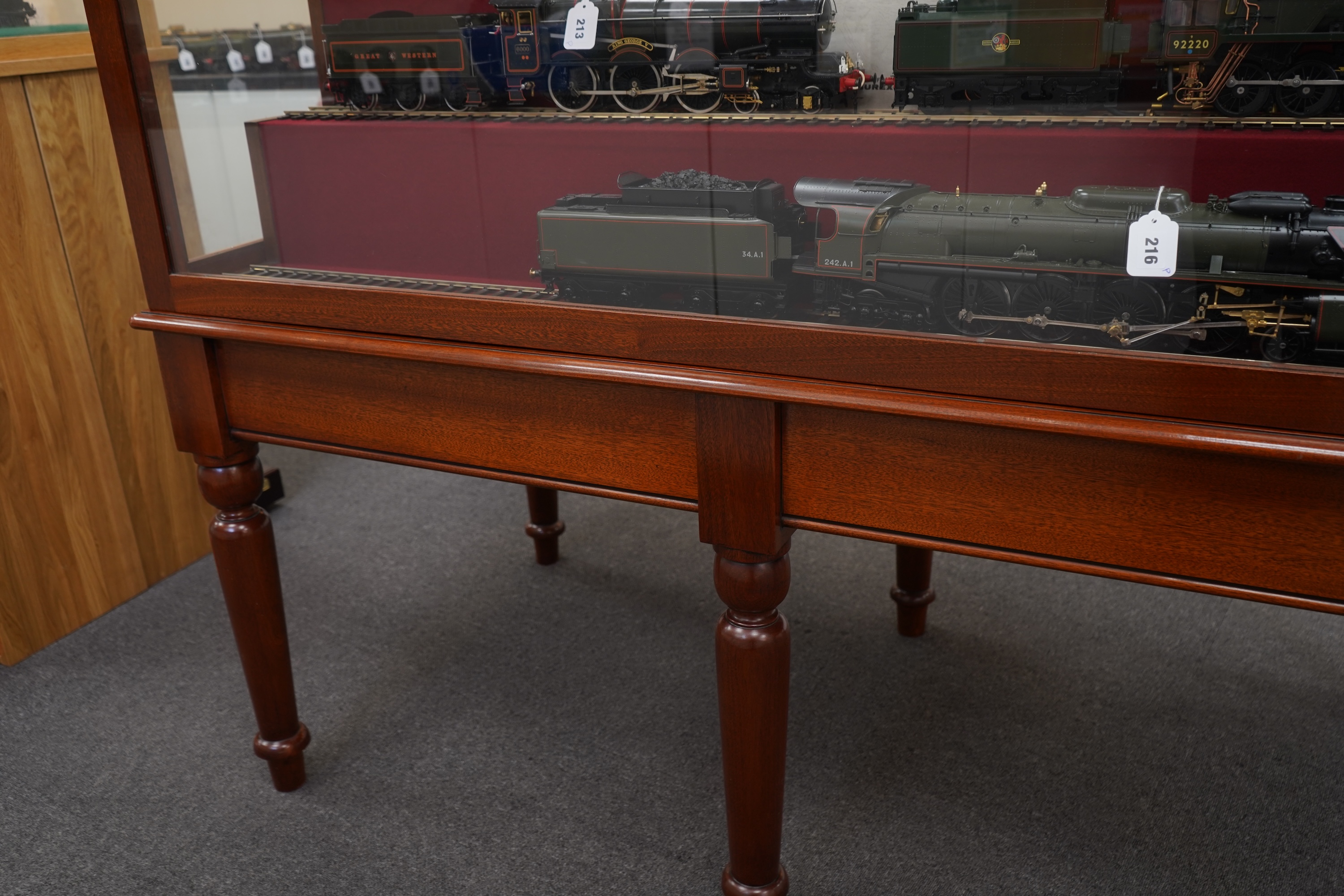 A substantial tiered display cabinet in a mahogany-tinted hardwood, with a lift off glazed cover, intended for Gauge One model railway rolling stock, currently fitted with five lengths of 45mm display railway track, dime